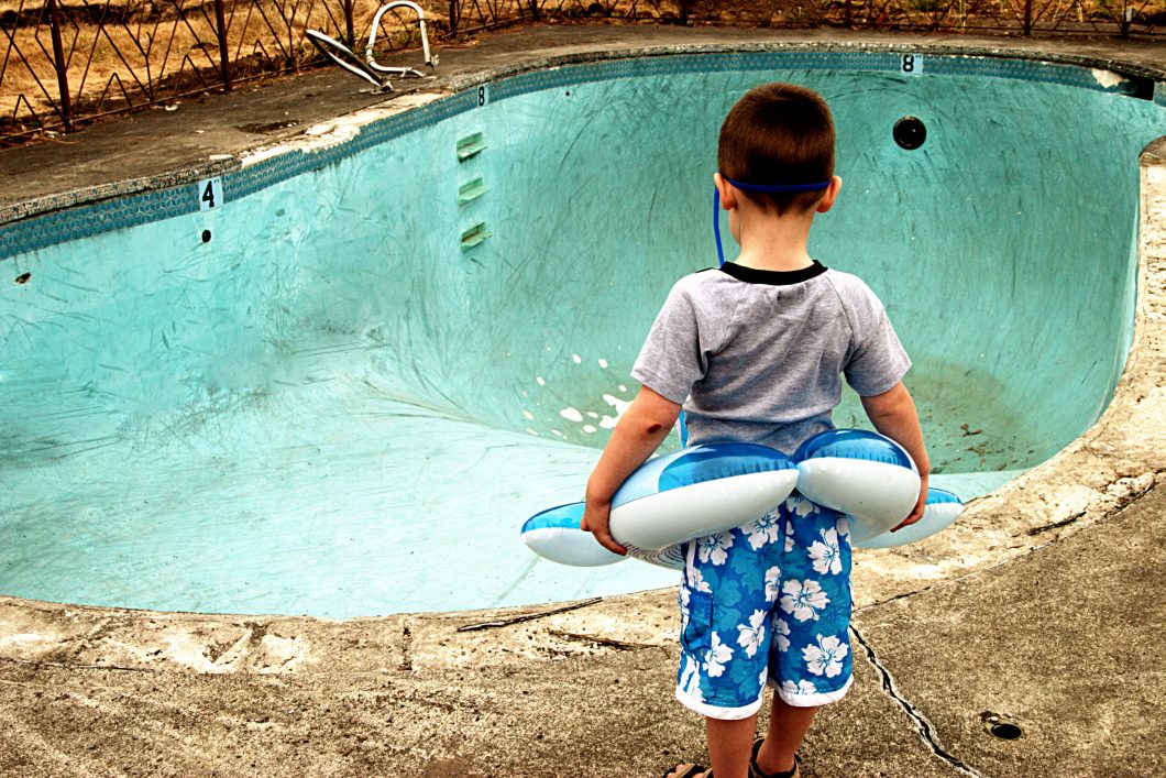 Small Boy Looking At Empty Pool By Ricklordphotography Via Istock