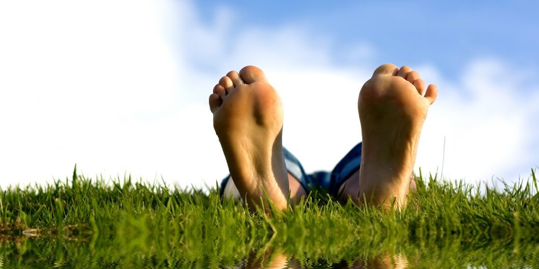 Feets On Grass Near Water.