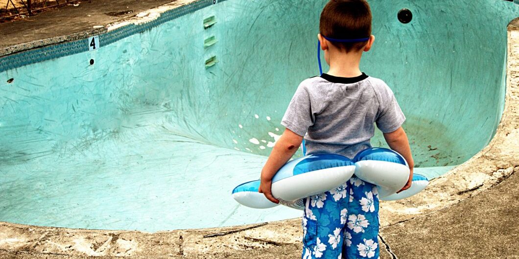 Small Boy Looking At Empty Pool By Ricklordphotography Via Istock